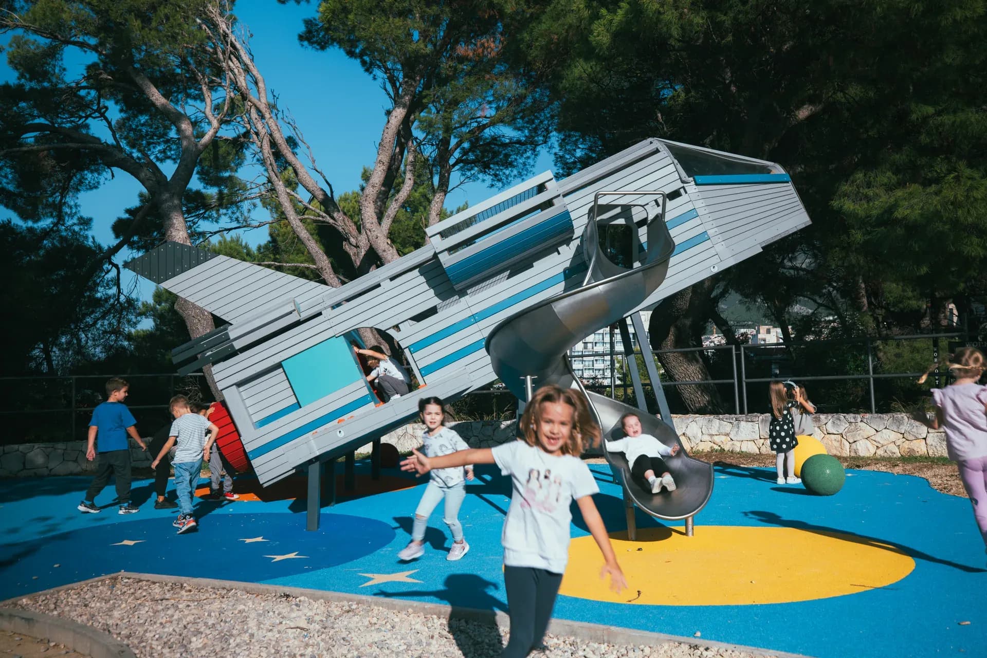 The full rocket structure at Makarska Observatory, seen from ground level with children playing nearby.