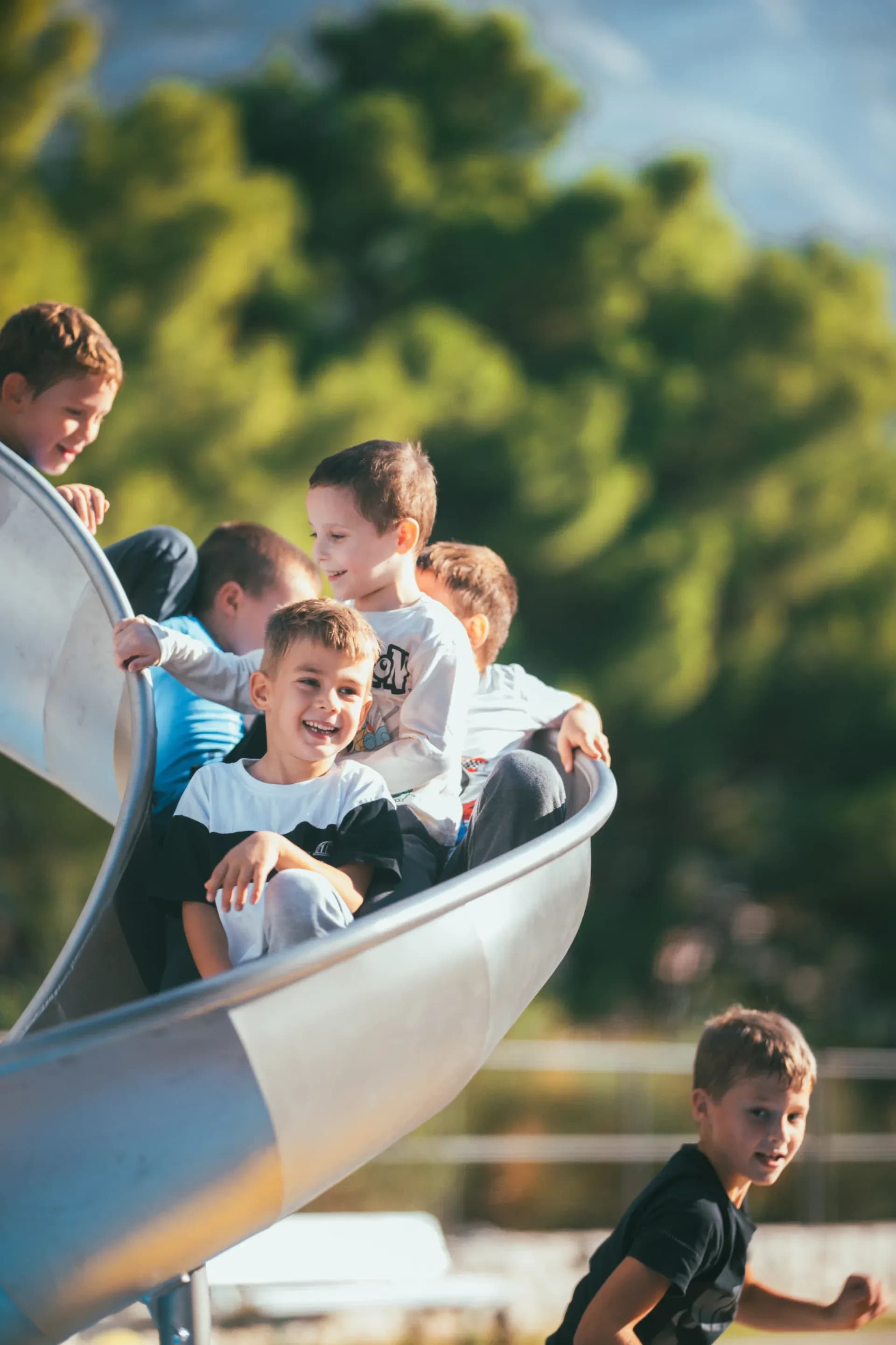 Multiple children sliding down the spiral slide together at the rocket playground, Makarska Observatory.