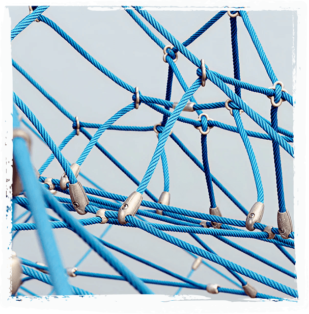 Close-up of blue playground climbing net ropes crossing at metal connector fittings, against a pale sky.