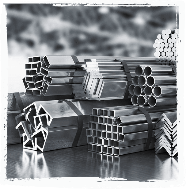 Bundles of stainless steel profiles, square and round tubes and angle sections, stacked in a warehouse.
