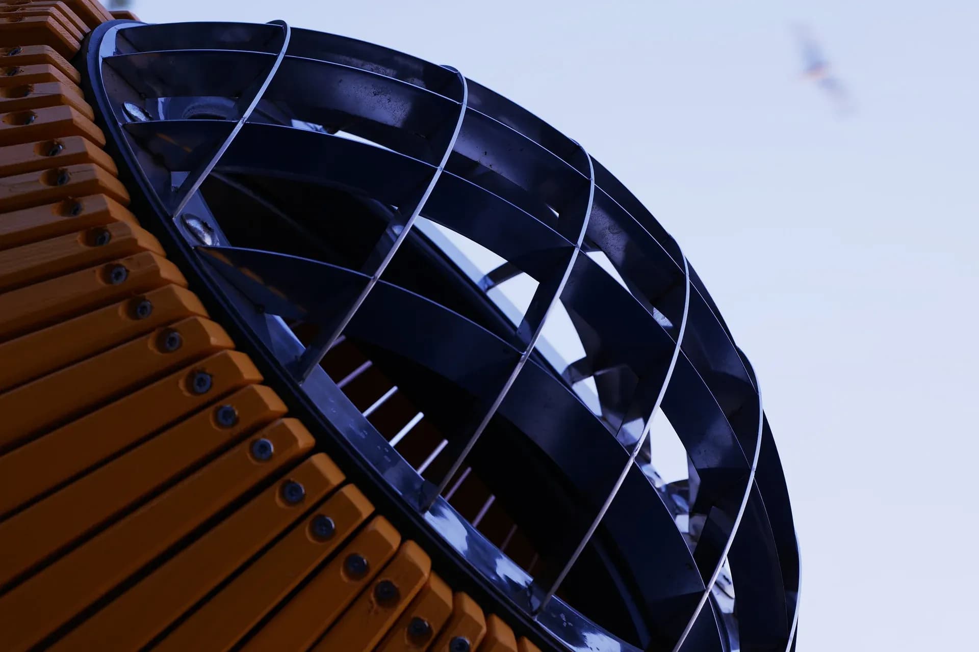 The stainless steel grille of the periscope port, seen from below against the sky, with a gull in flight