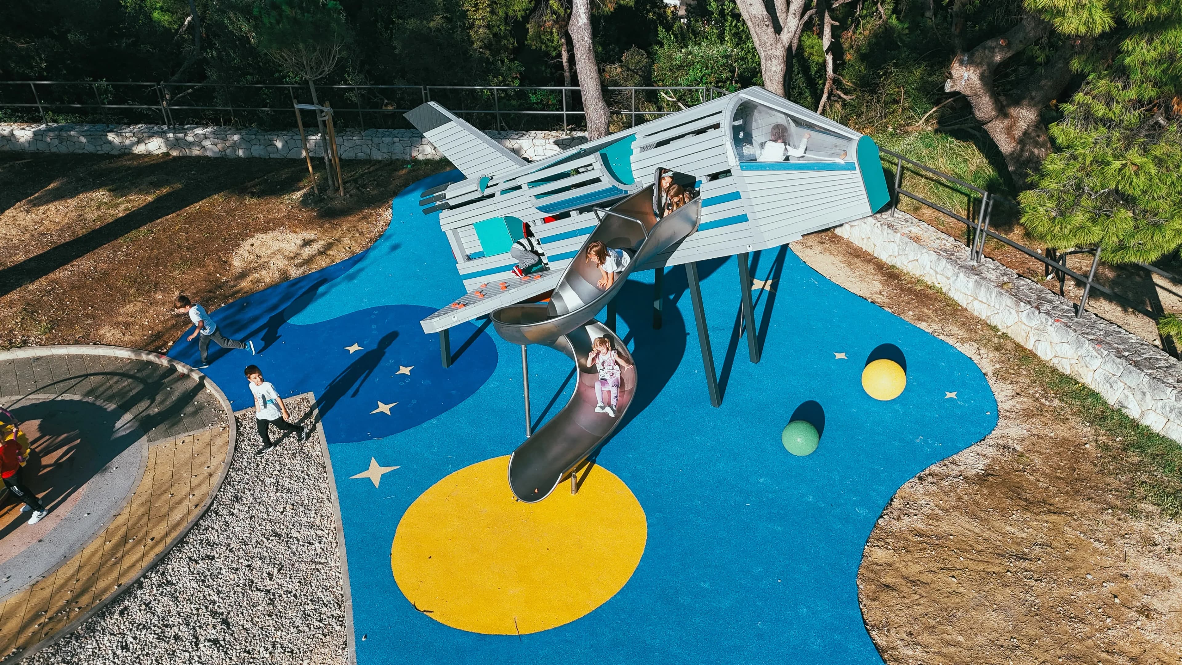 Aerial view of the rocket-shaped playground structure at Makarska Observatory, with its spiral slide and themed space surfacing.