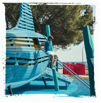 A child sliding down the boat structure at Sea World, with a climbing feature visible nearby.