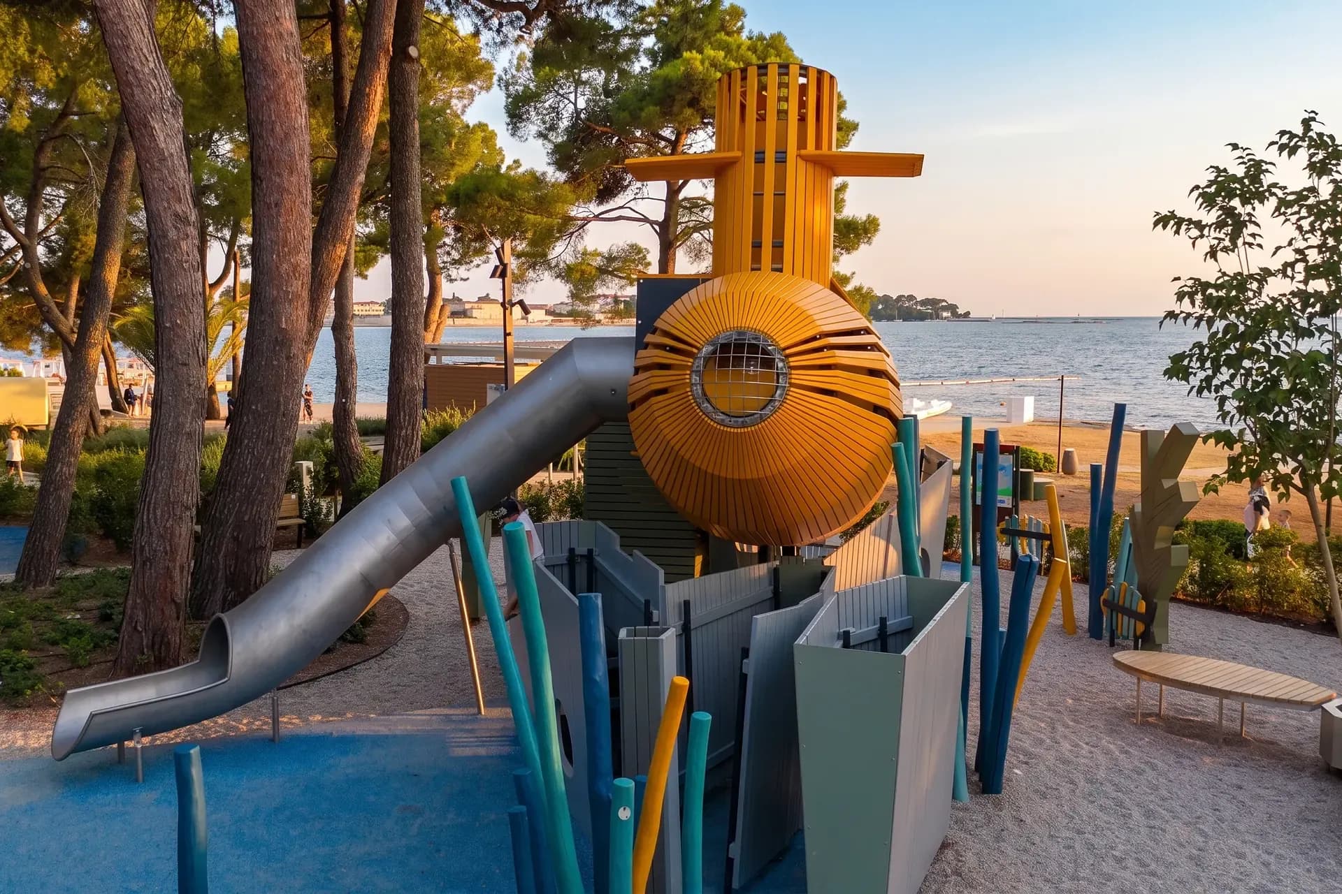 The bow of the yellow submarine with the periscope port, the stainless steel tube slide and the coloured columns, with the Poreč shoreline behind, Yellow Submarine playground