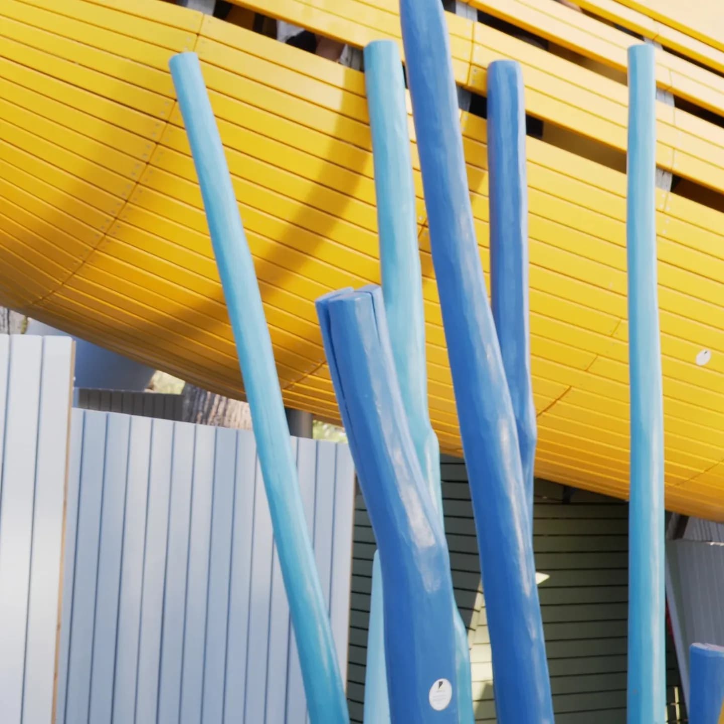 The turquoise and blue columns of the Yellow Submarine playground seen from below, with the yellow submarine hull curving above them, Valamar Pical Resort in Poreč