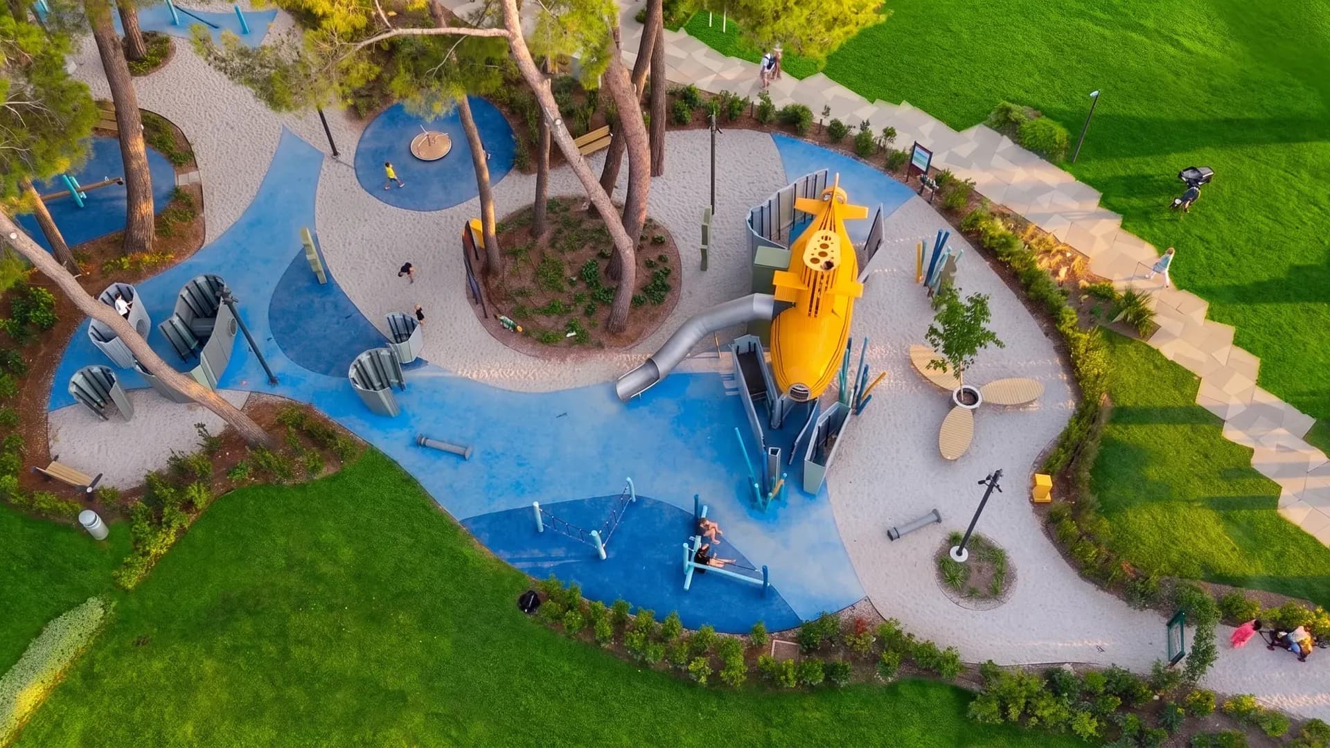 Top down aerial view of the 700 square metre Yellow Submarine playground, the blue surfacing, the stone labyrinth and the yellow submarine among the pines, Valamar Pical Resort
