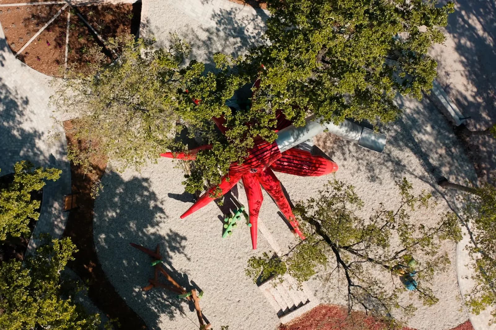 Aerial view of the octopus playground at Glavotok, arms spreading across the gravel among oak trees.