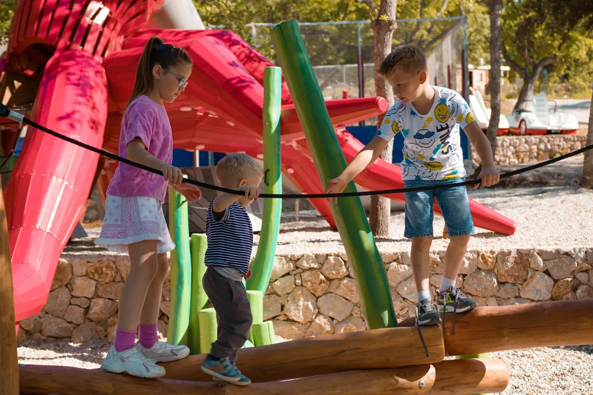 Children balancing together on a log beam near the octopus structure at Glavotok Campsite.