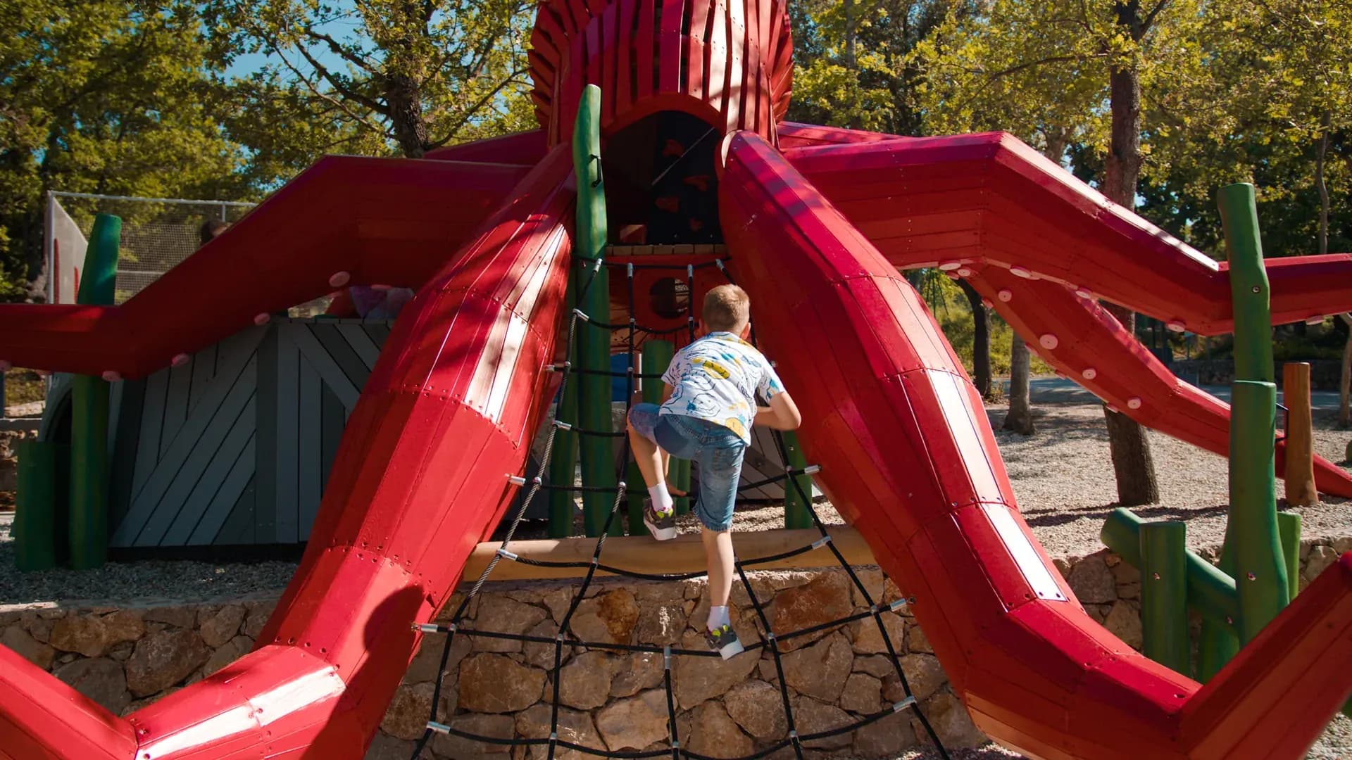 A child climbing the rope net into the octopus structure at Glavotok Campsite.