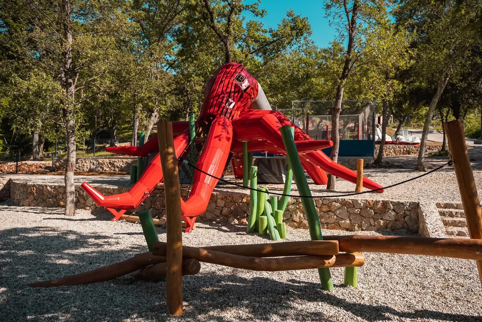 The octopus structure at Glavotok Campsite in its setting, with the dry-stone wall, sea grass elements and oak forest.