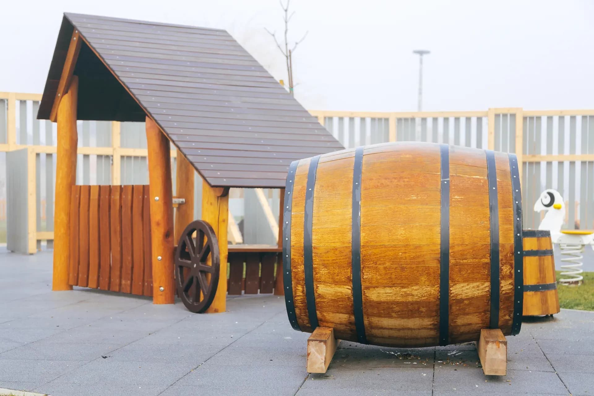 A rustic market stall with a cart wheel and oak barrel at the Timeless Legends playground.